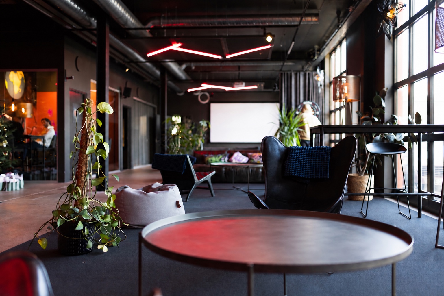 Lounge med sittgrupper, gröna växter och stora fönster